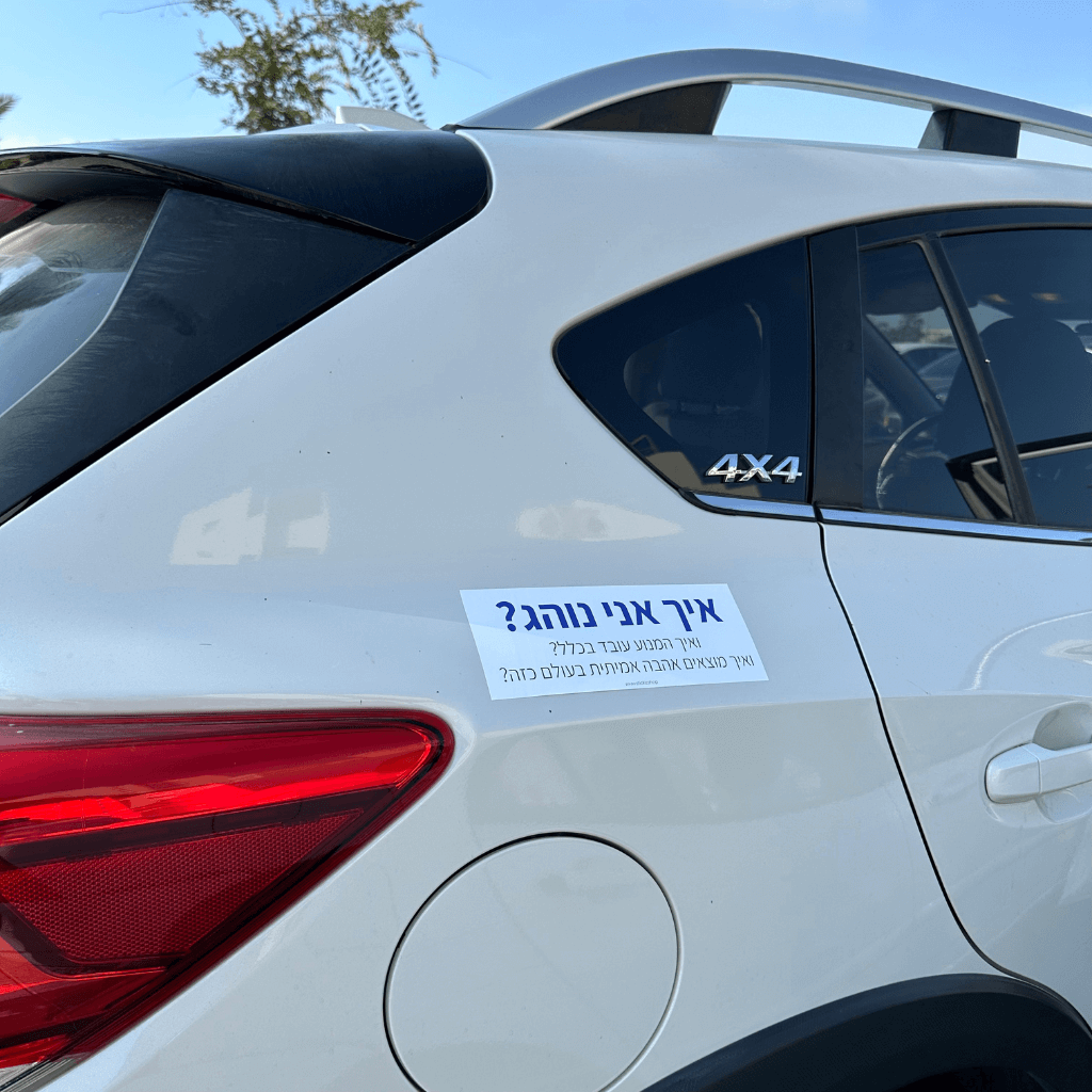 מדבקה לרכב איך אני נוהג? ואיך המנוע עובד בכלל? ואיך מוצאים אהבה אמיתית בעולם כזה?, מודבקת על רכב לבן