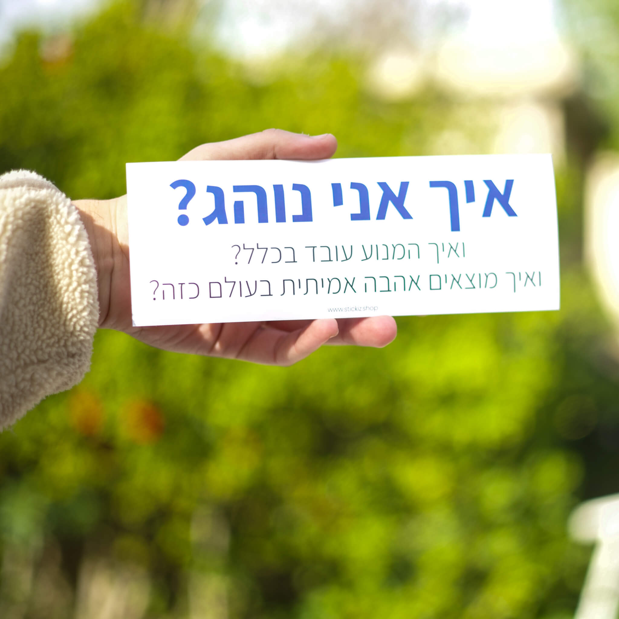 מדבקה לרכב איך אני נוהג? ואיך המנוע עובד בכלל? ואיך מוצאים אהבה אמיתית בעולם כזה?, מוחזקת ביד